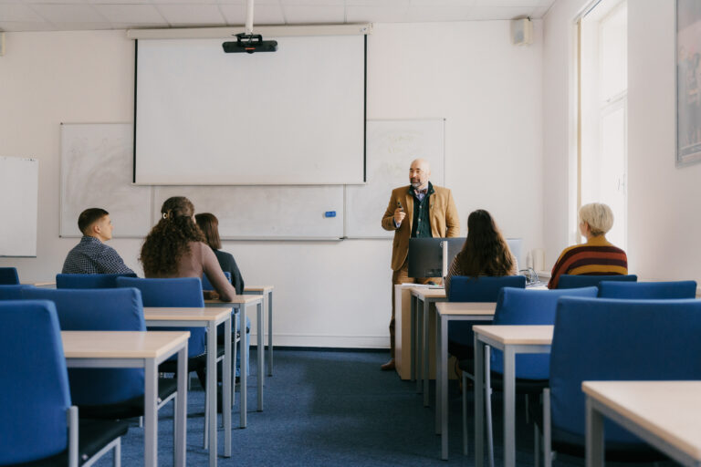 Anthony Prochazka standing at the front of a classroom during a lecture at the University of New York in Prague